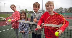 four juniors with rackets on a net