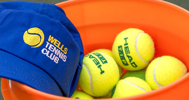 PIcture of a Wells Tennis Club hat and balls in a bucket