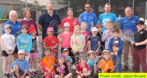 Children with their rackets standing and sitting infront of members of Wells Tennis Clubs committee