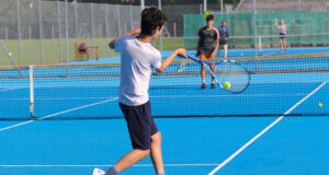 child hitting a forehand on a blue court