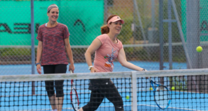 two female tennis players hitting balls on a blue court